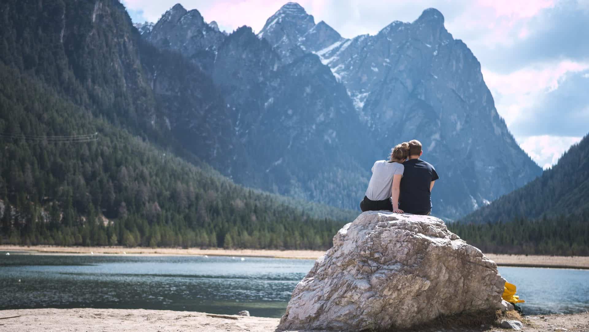 Photo of a heterosexual couple cuddling in front of mountains