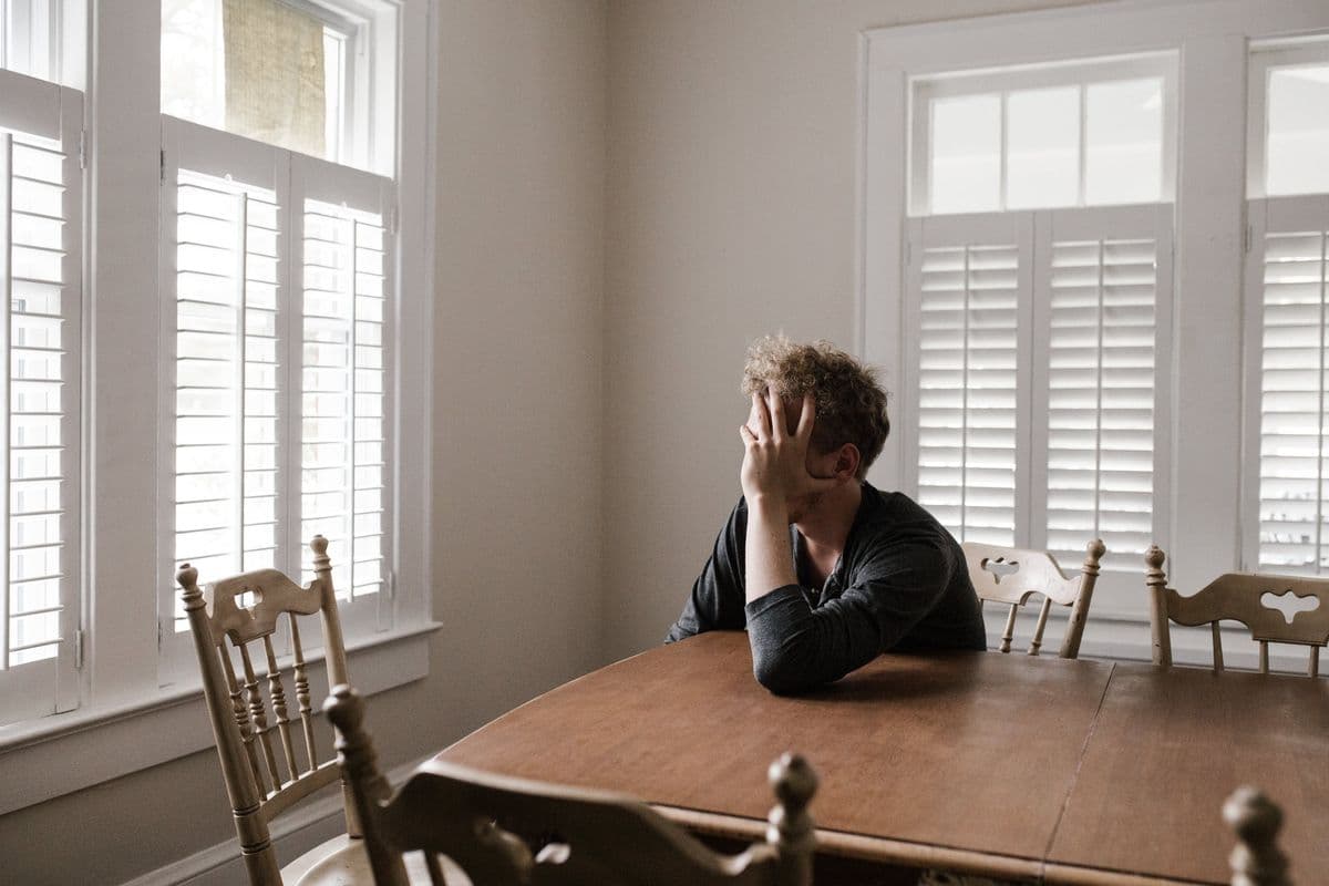 A sad man sits at a table, by Andrew Neel via Pexels