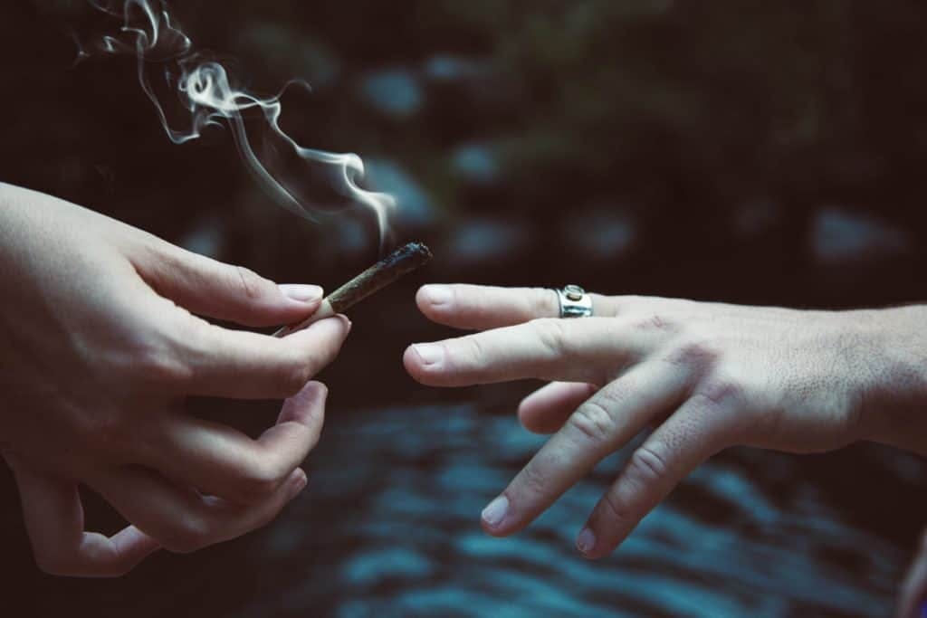 Two people pass a joint from one to the other, by Jeff W via Unsplash