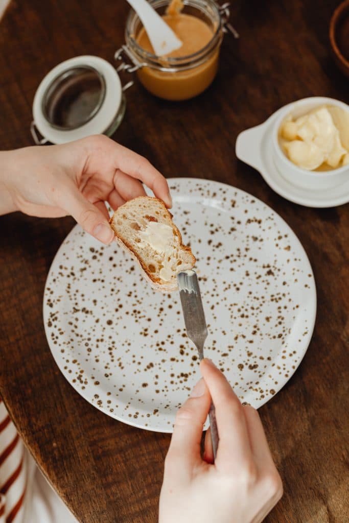 Spreading butter on a piece a crusted bread