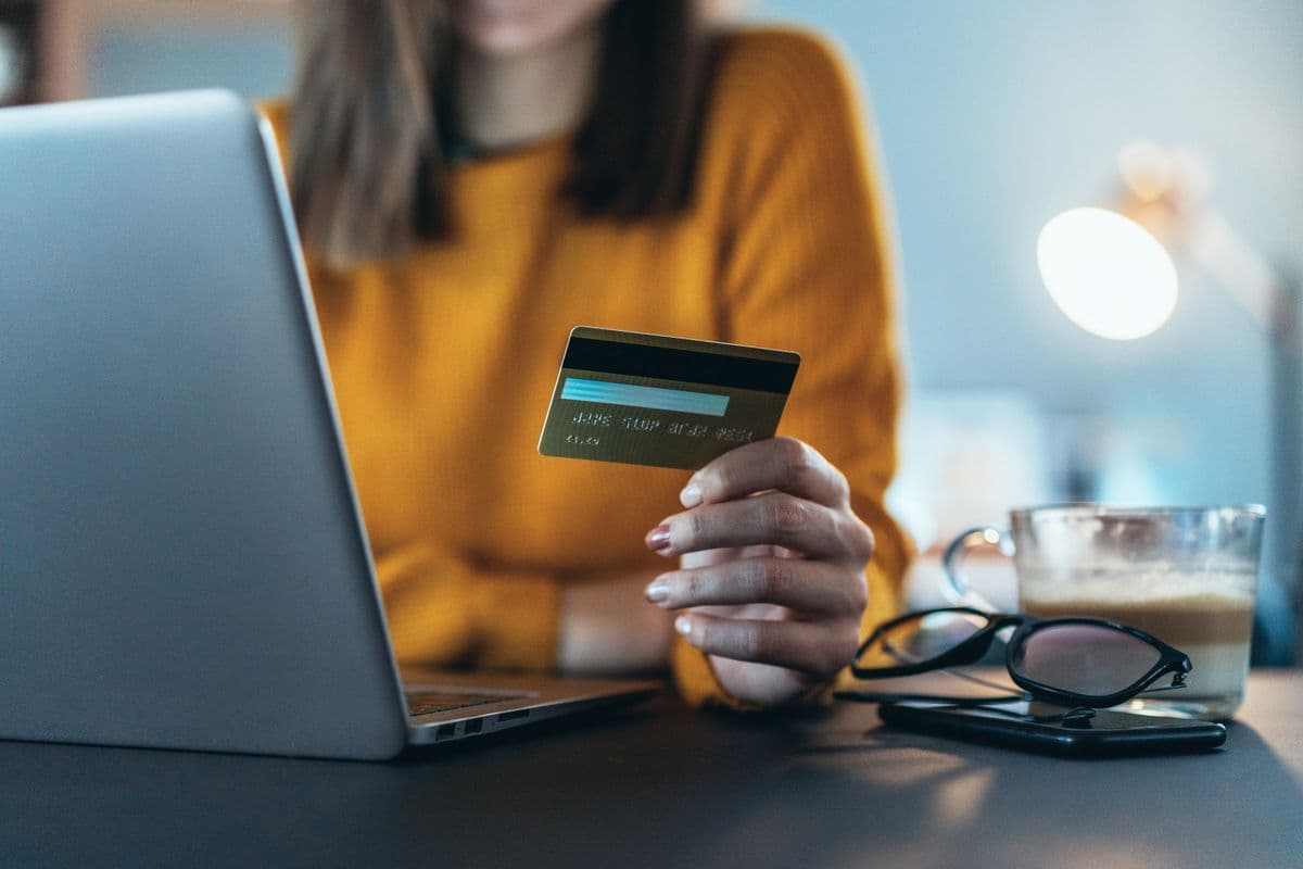 A woman holding a credit card prepares to purchase something online. If it's weed, we hope she's read our article!