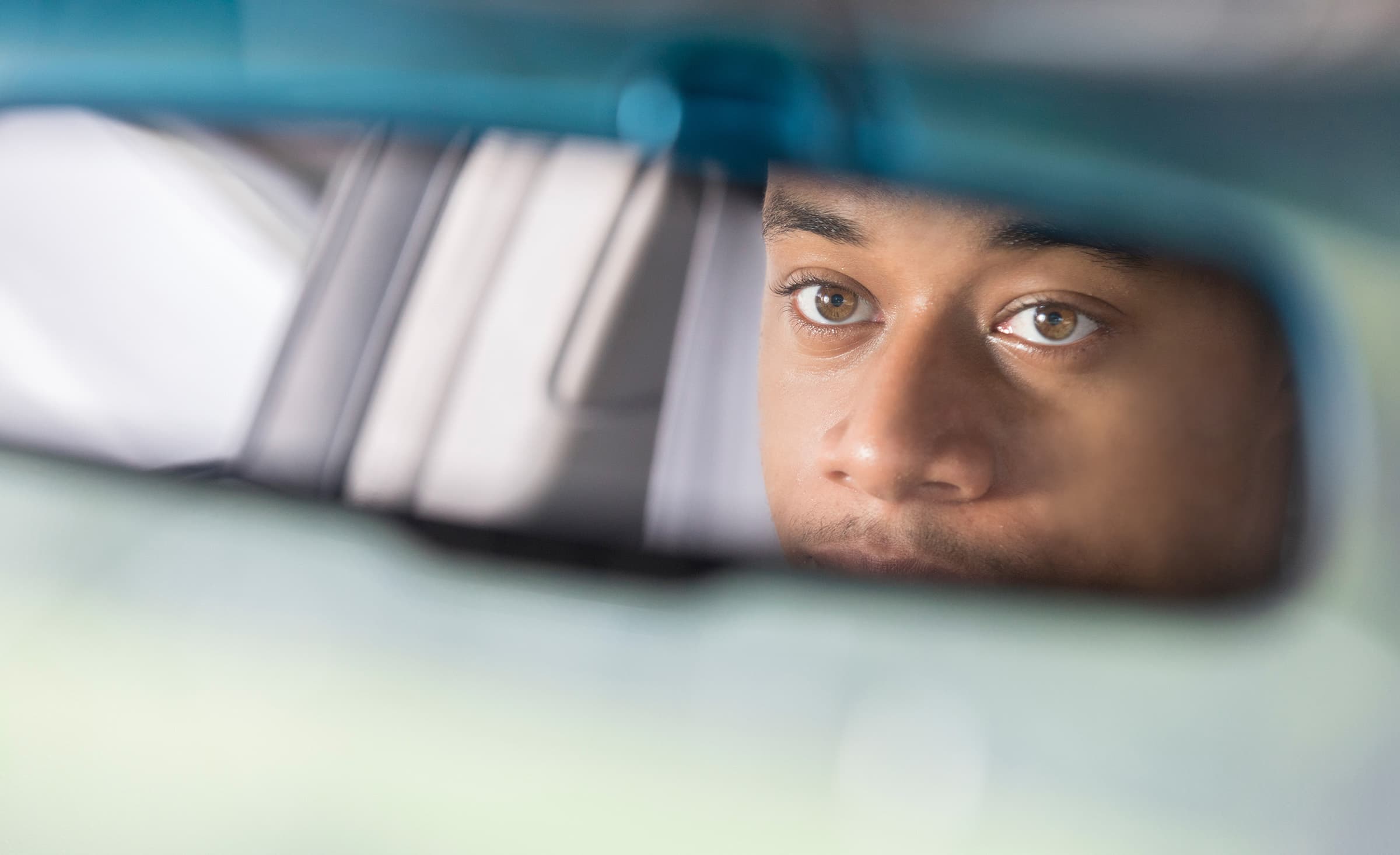 reflection of man's eyes in the rear view mirror of a car