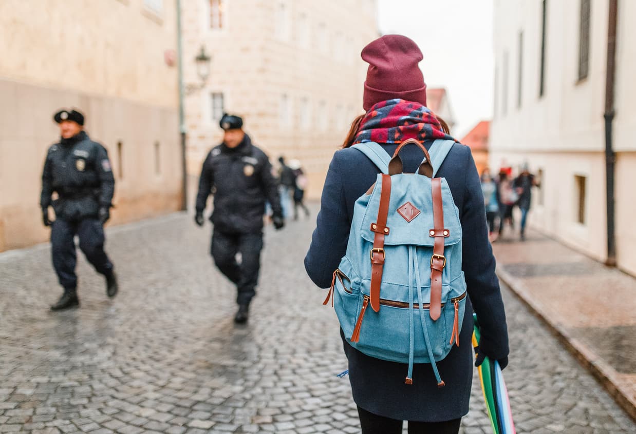 A woman tourist walks down the street against a background of two policemen