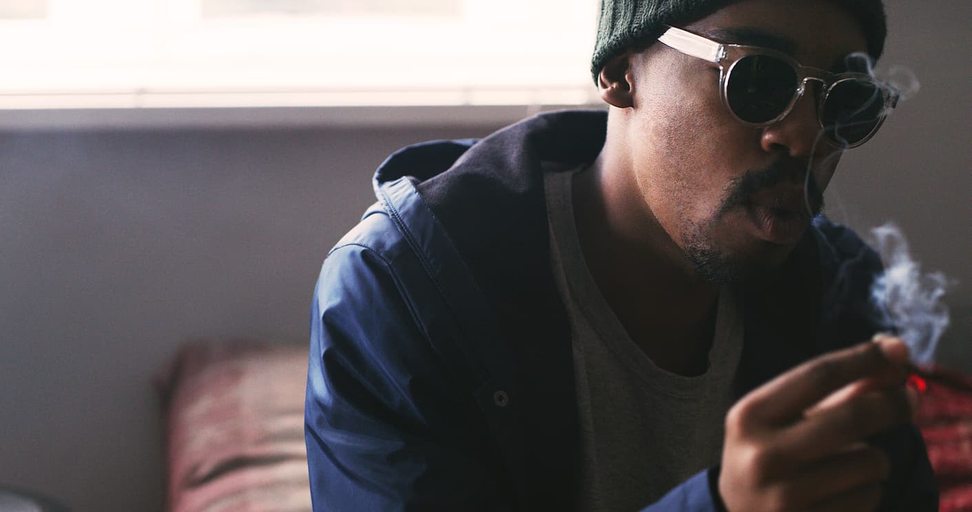 Shot of a young man smoking a marijuana joint at home