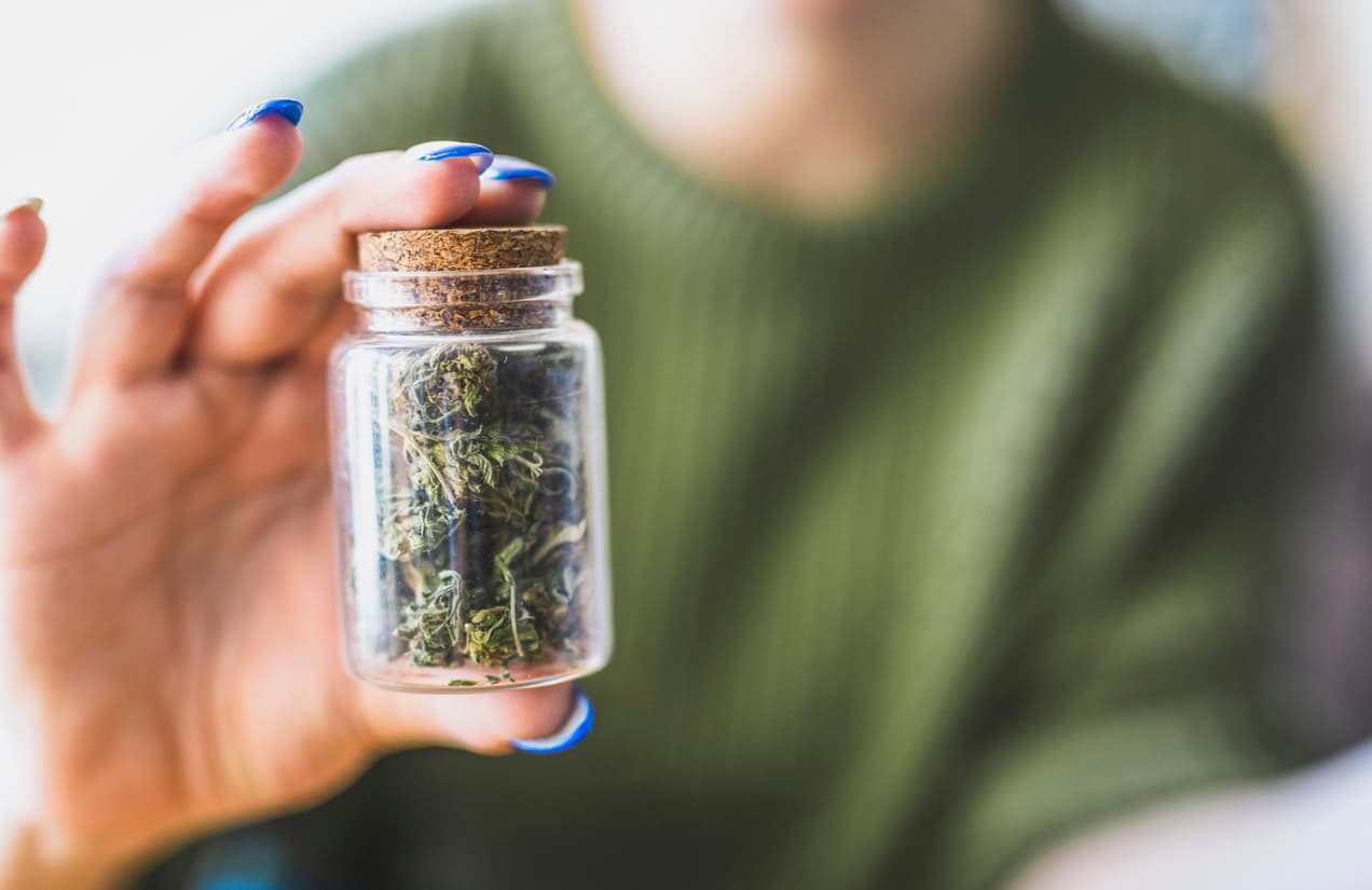 Unrecognisable woman holding a jar full of marijuana.