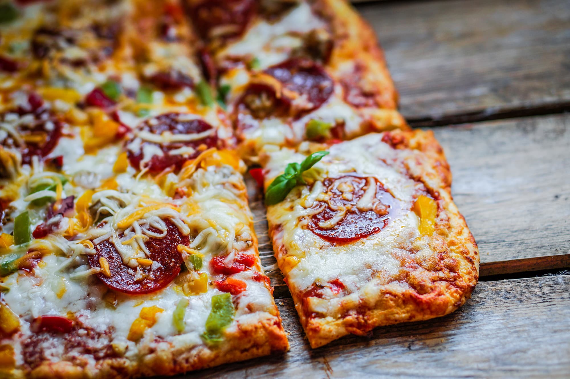 Square pepperoni pizza on rustic wooden background