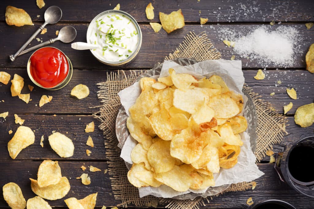 Potato chips with dipping sauces on a rustic table. Photographed from directly above.