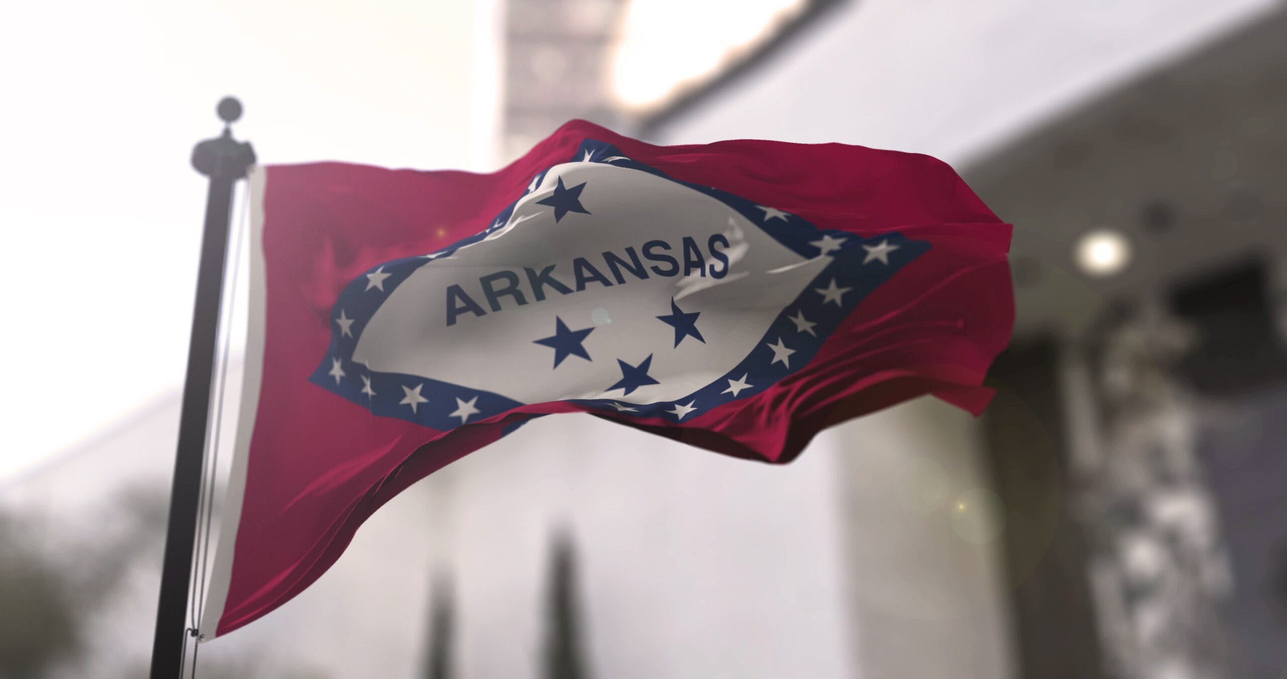Arkansas state waving flag on blurry background, USA state news illustration. Blurry background.