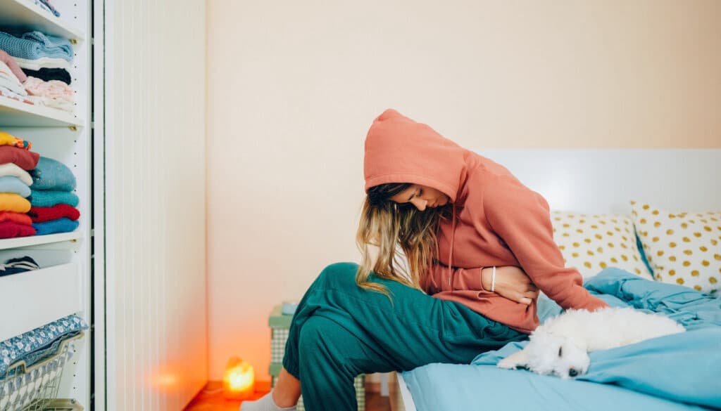 Young woman with painful stomach pain resting in bed