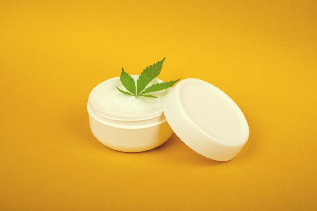 cannabis cosmetics , natural marijuana cream and green leaf on beauty yellow background.