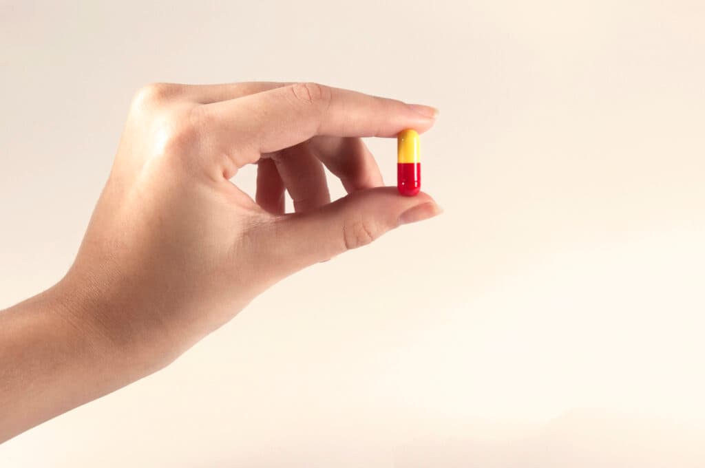 Caucasian Woman Holding a Pill on White Background / Capsules and Pills / Medicine