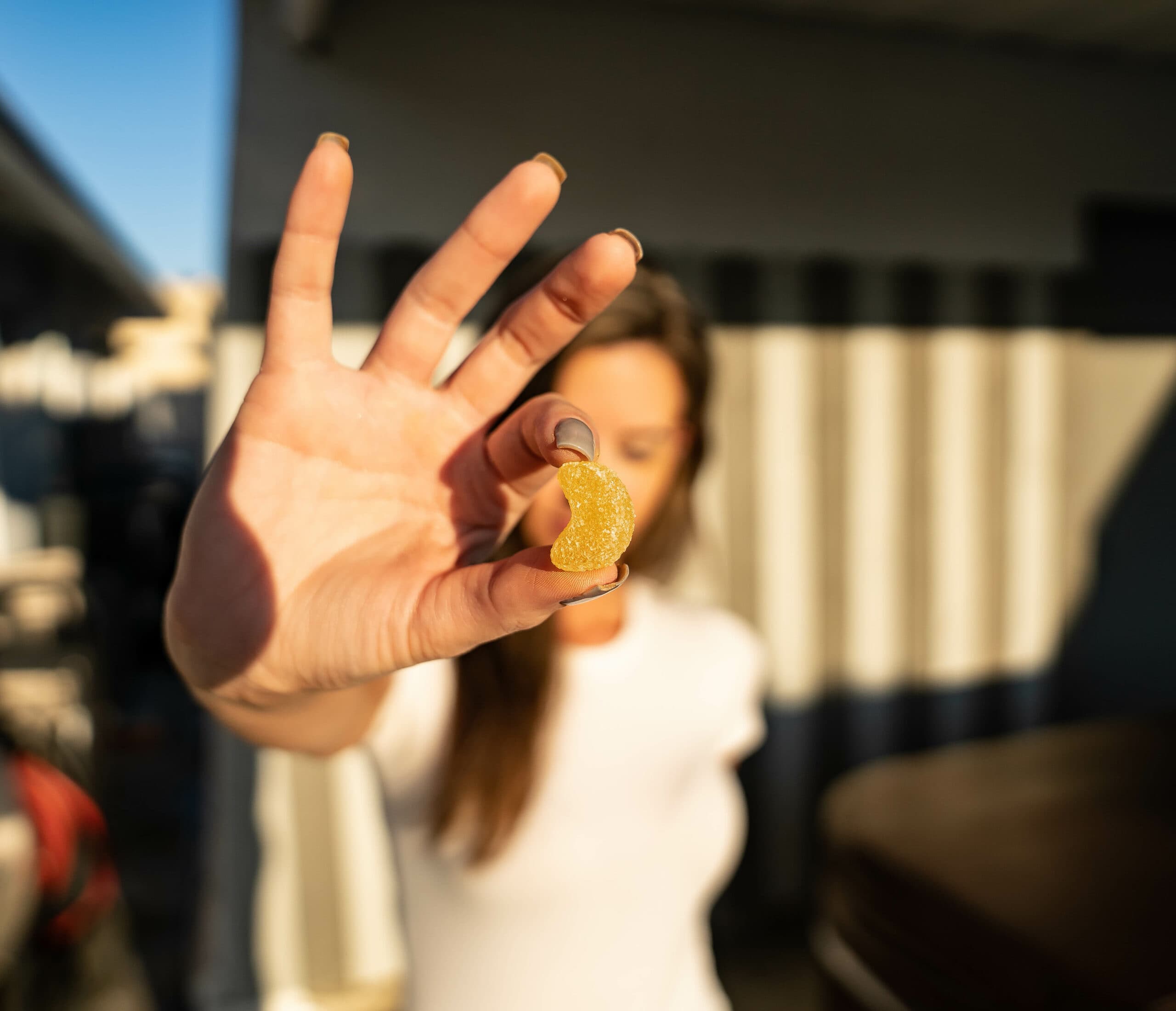 woman holding CBD THC gummy in front of face