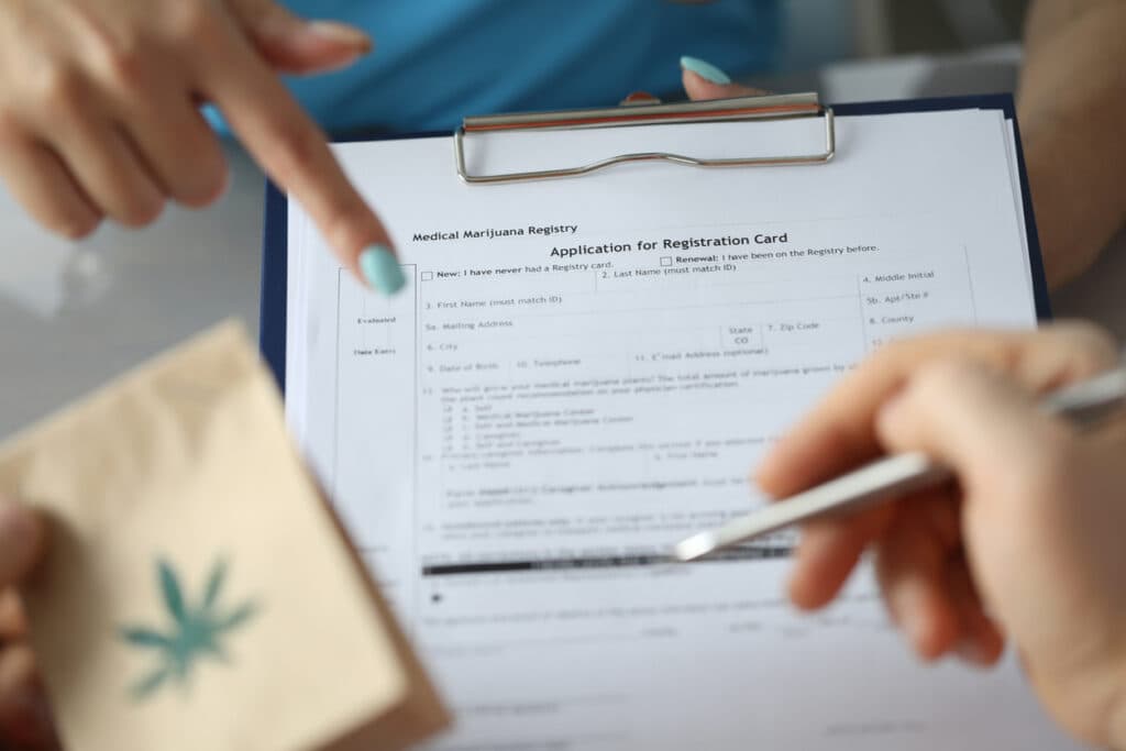 Focus on female hand holding paper folder and pointing for text. Sick patient with paper package with cannabis symbol on it and signing document. Healthcare and medical marijuana concept