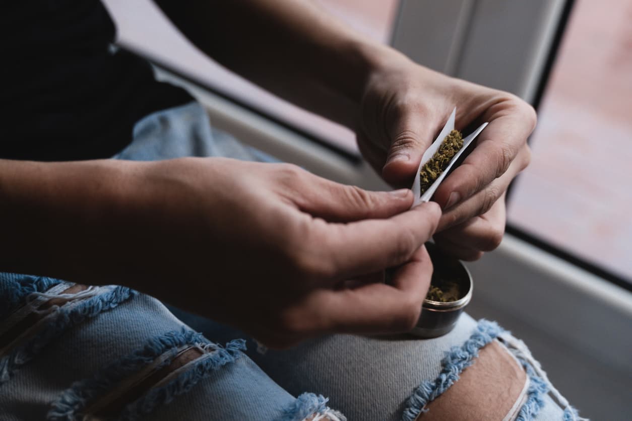 Medicinal cannabis cbd concept - Young man rolling marijuana spliff - Focus on right hand