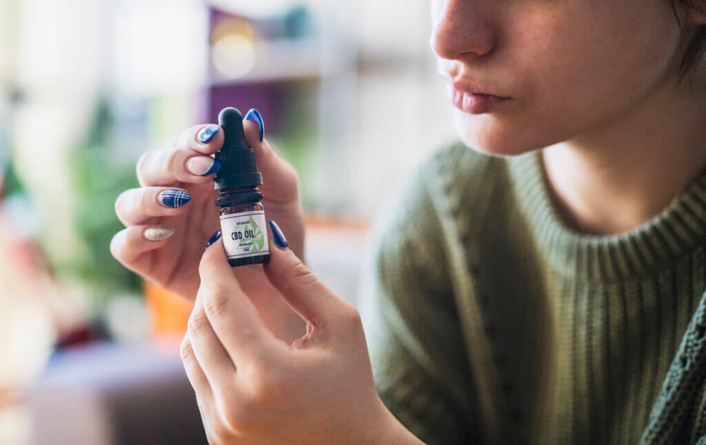 Unrecognisable woman holding CBD oil drops.