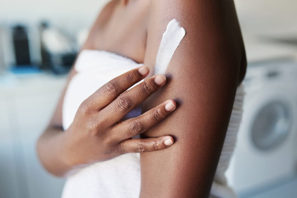 Cropped shot of a woman applying moisturiser to her body