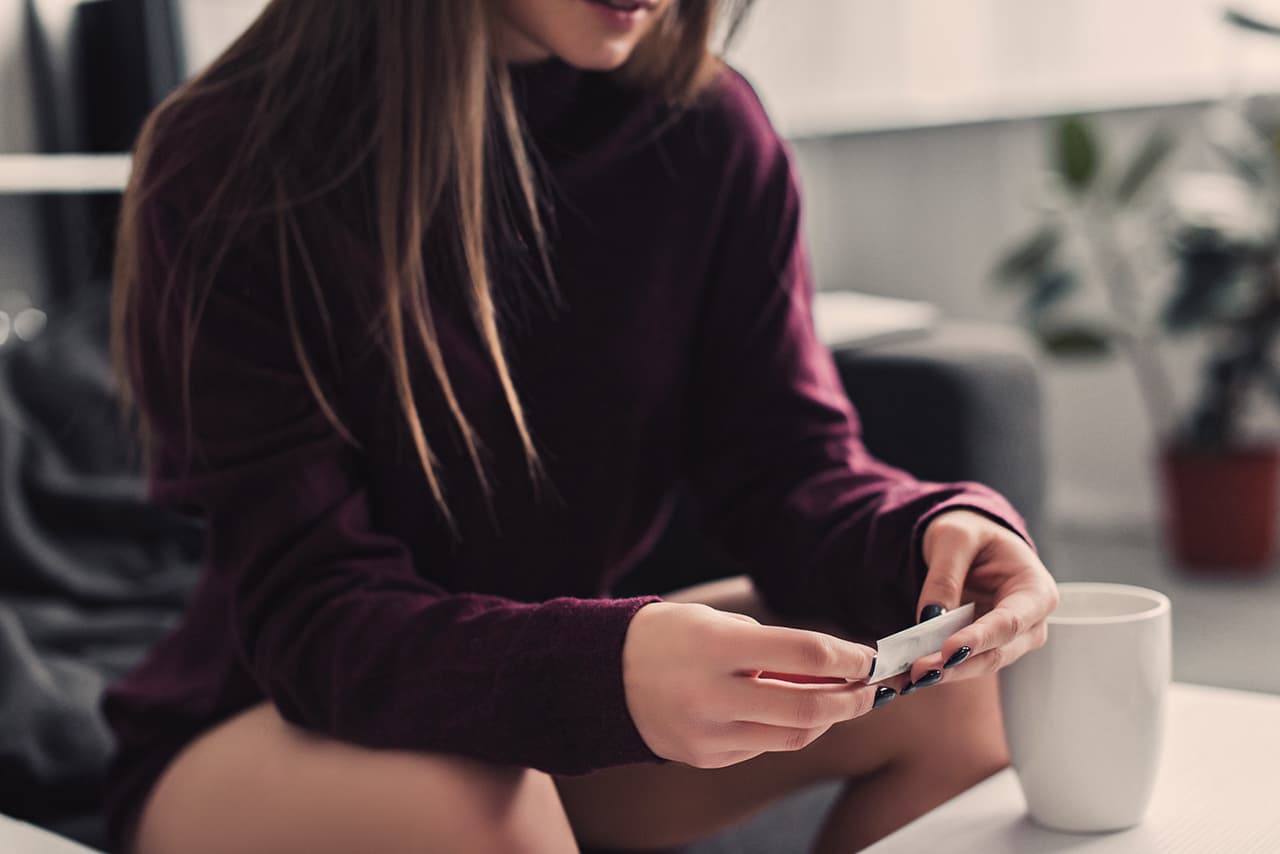 partial view of girl sitting and rolling marijuana joint at home