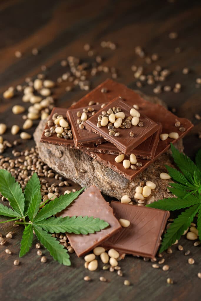 CBD Chocolate with pine nut, cannabis leaves and seeds on wooden background. Healthy take of break