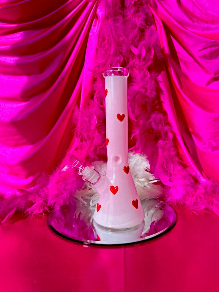 a pink glass bong with red hearts