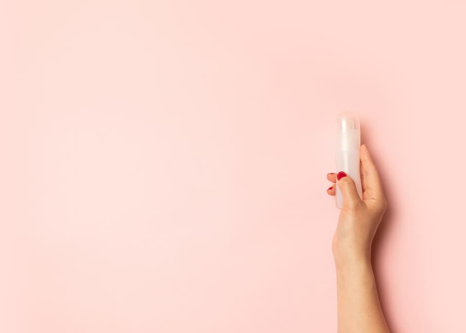 Loneliness, no relationship concept. Womens hands hold intimate grease and a red heart shape on a pink background