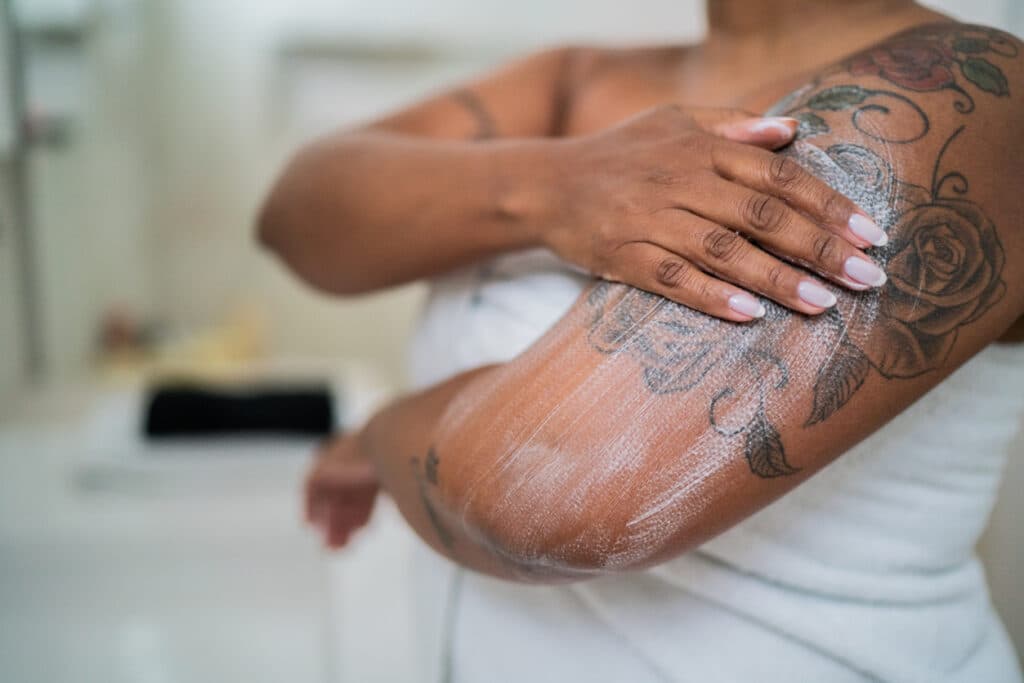 Woman applying body mosture in the bathroom at home