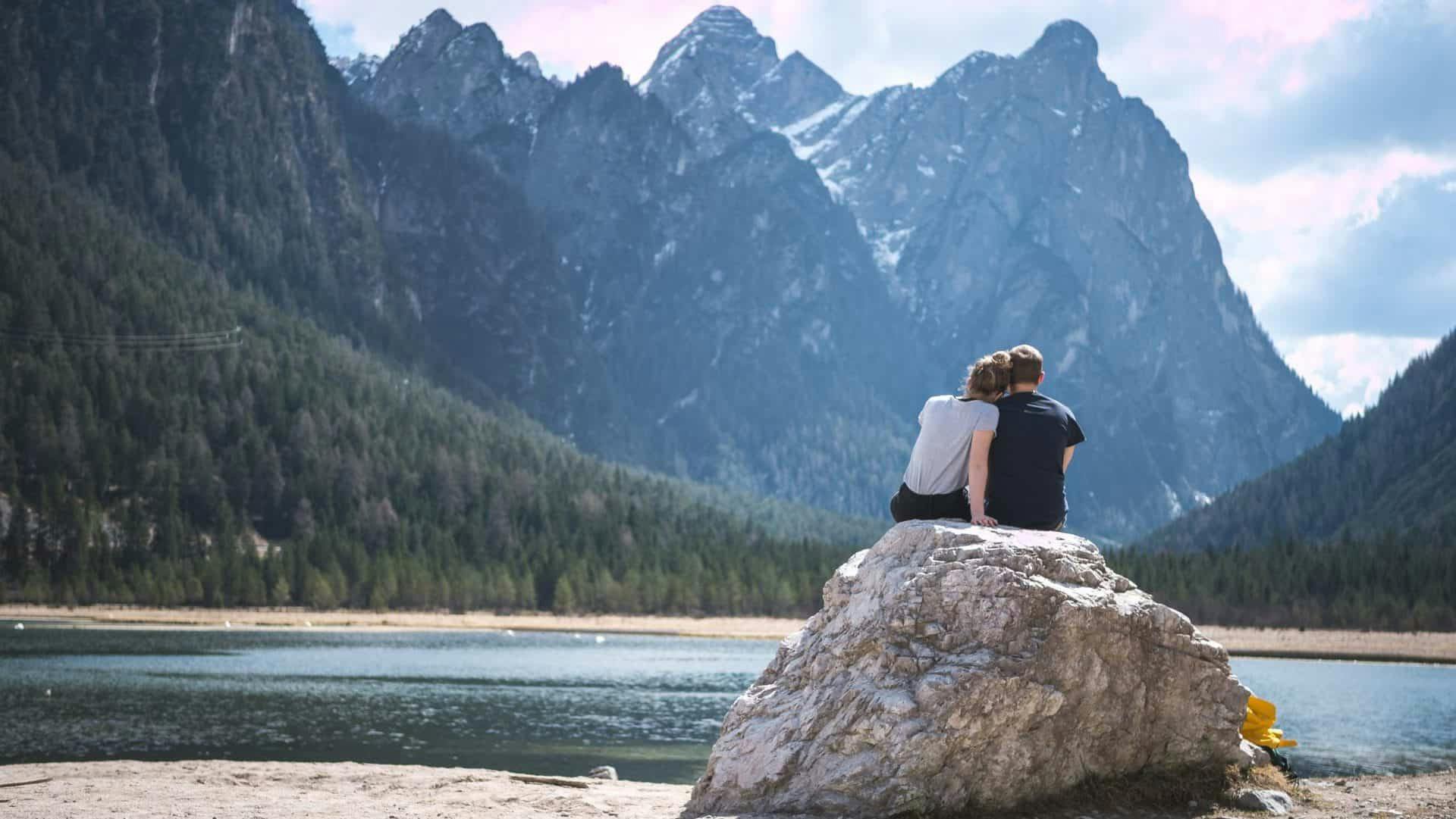 Photo of a heterosexual couple cuddling in front of mountains