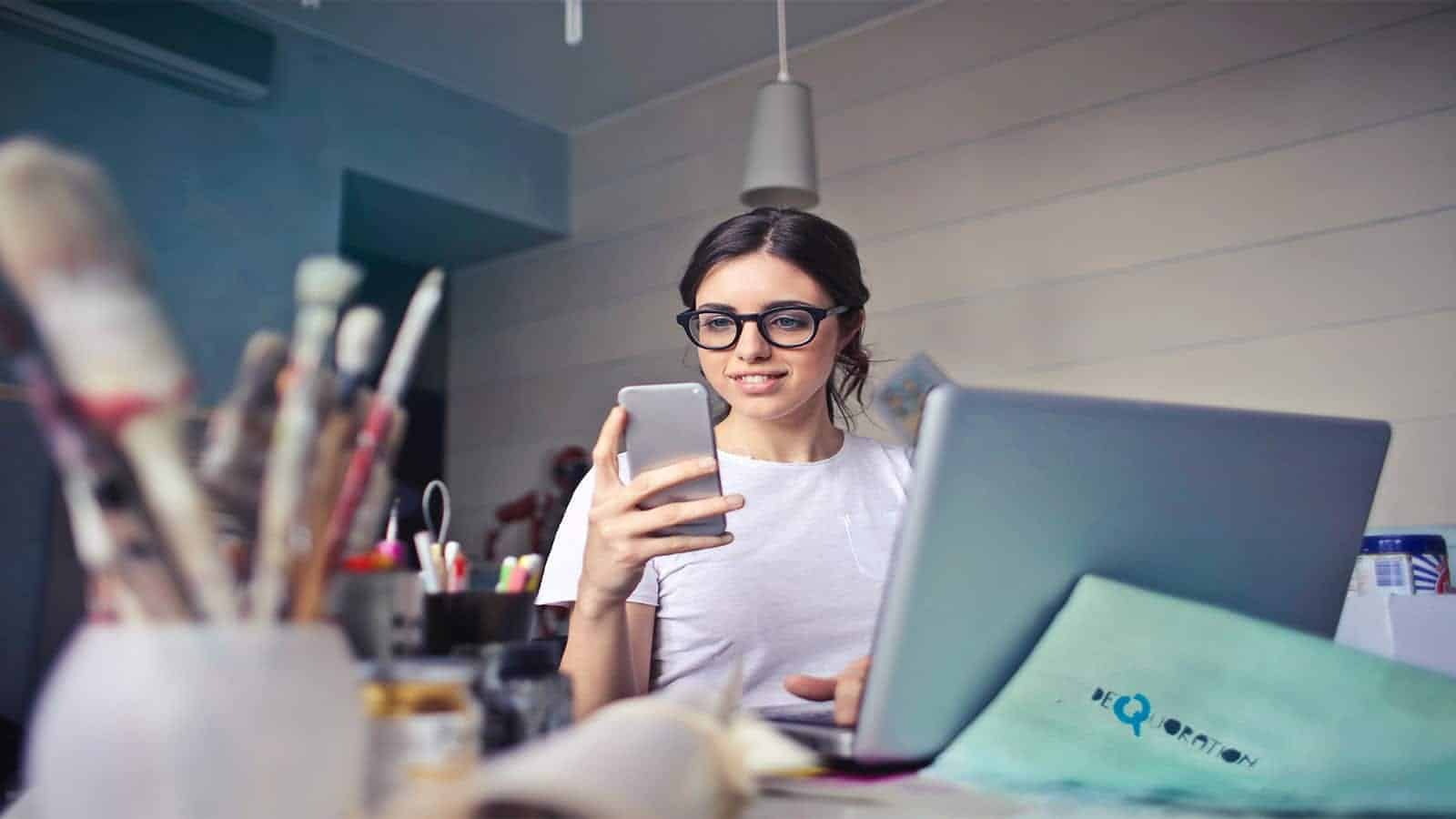 photo of a women smiling at her cell phone while doing work