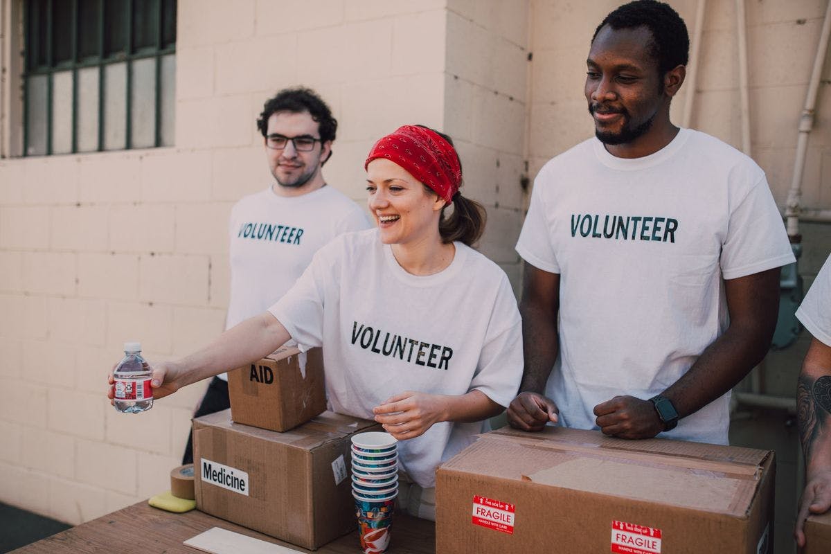 A group of volunteers hand out bottles of water, by RODNAE Productions via Pexels