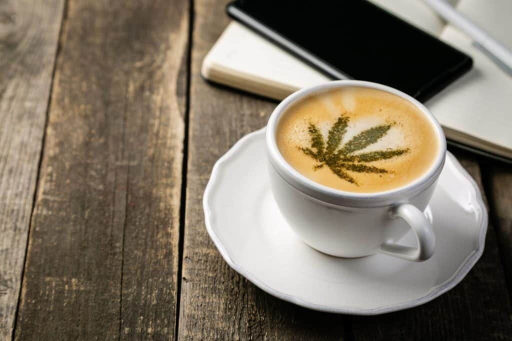 Cup of coffee with cannabis leaf sitting in foam