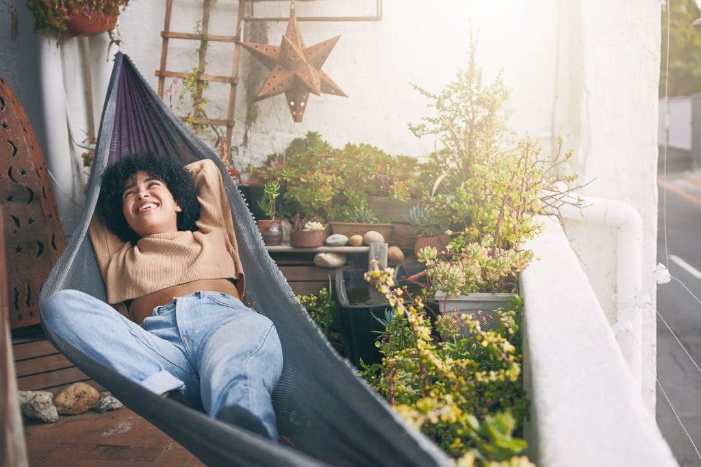 A woman relaxes in a hammock, surrounded by greenery and good vibes. By Rowan Jordan via iStock