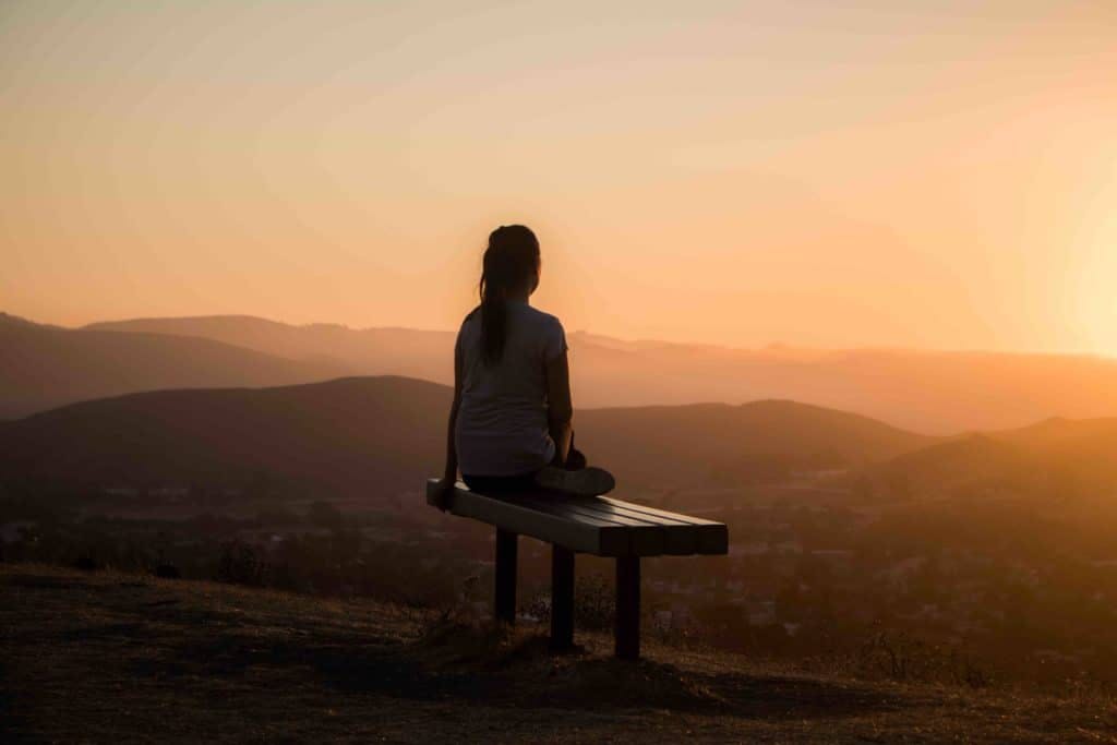 Girl meditating looking at a sunset