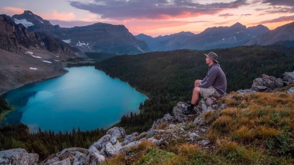 Young man sitting on a cliff in the rockies