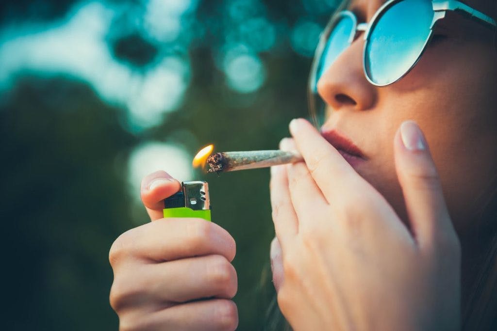 A woman lights a joint, by LordHenriVoton via iStock