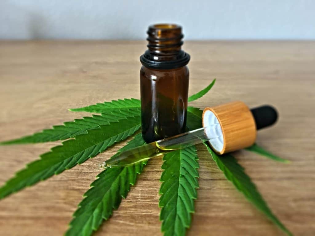 Amber oil dropper bottle sitting on a cannabis leaf