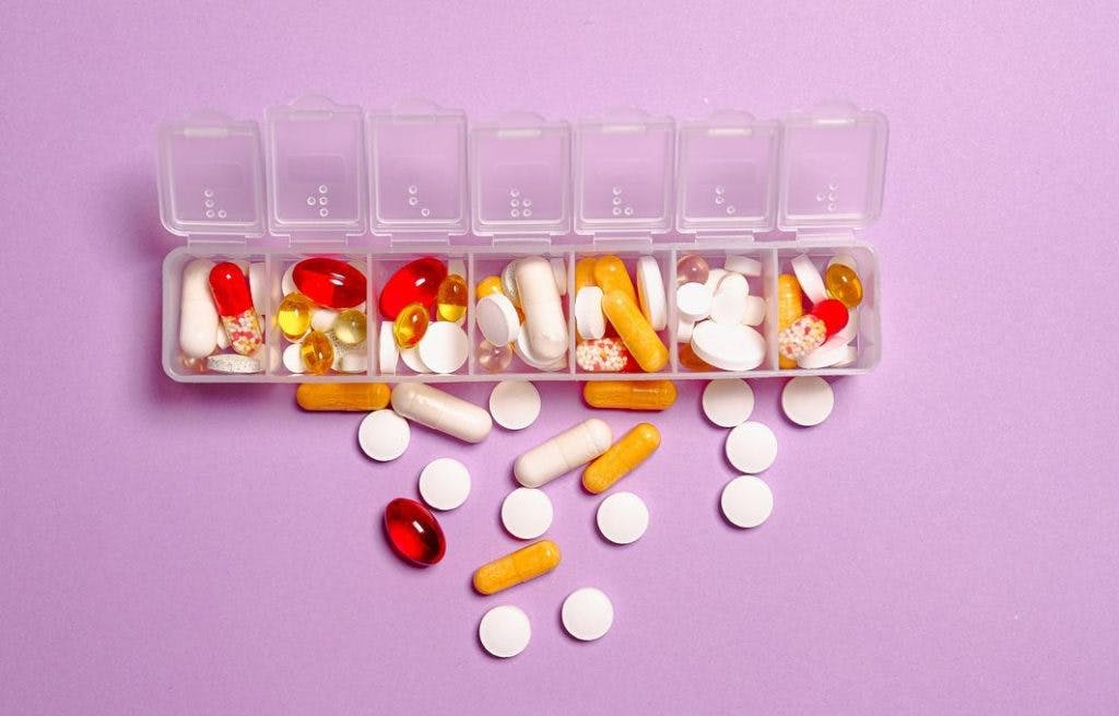 Assorted pills on a pink background