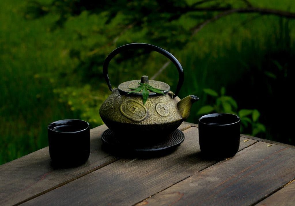 A tea pot with a leaf sitting on top.