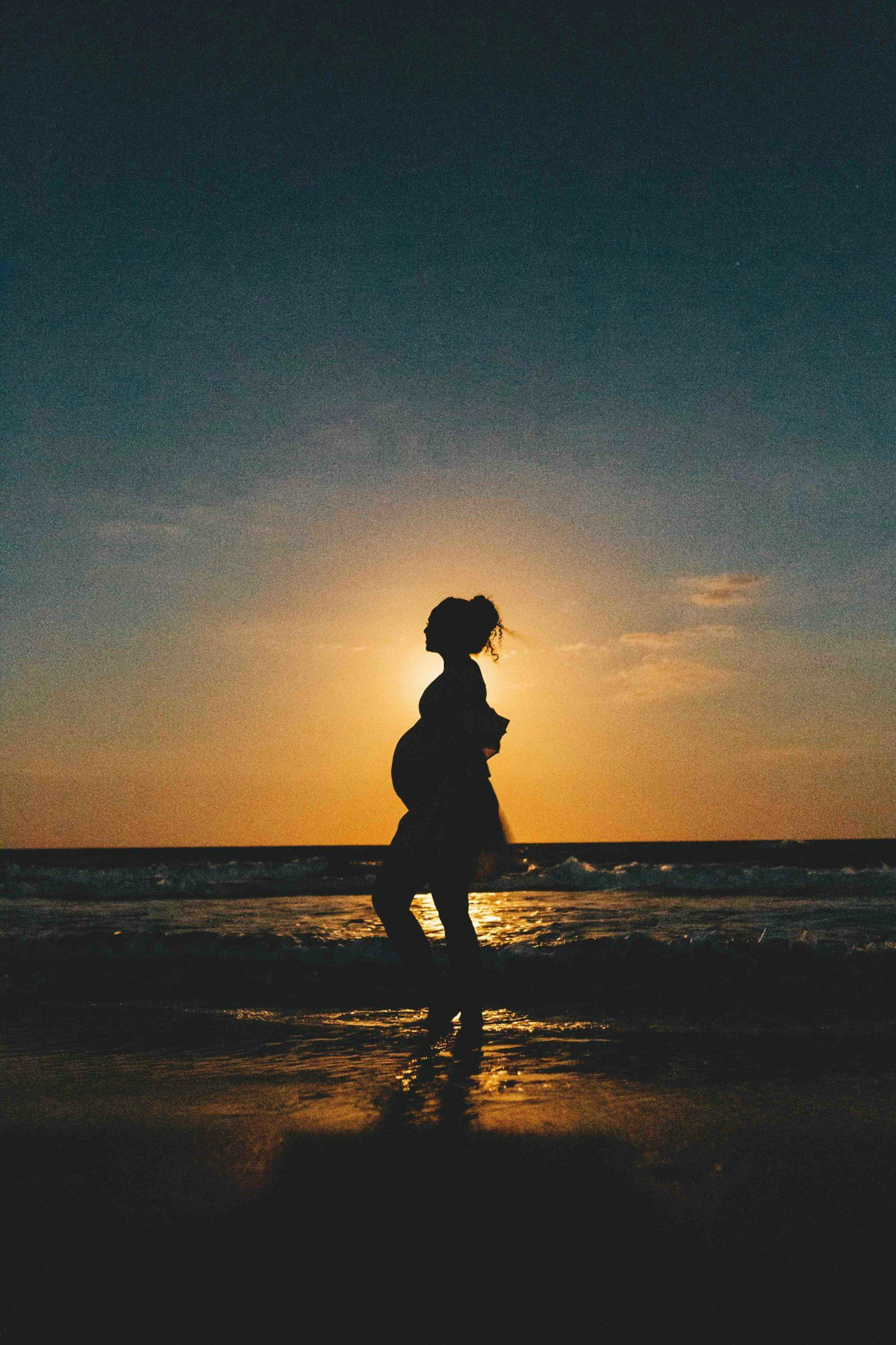 pregnant woman on beach at sunset