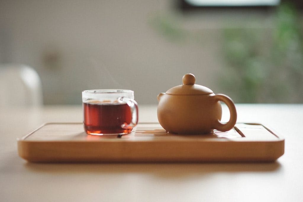 A cup of tea, next to a clay tea pot