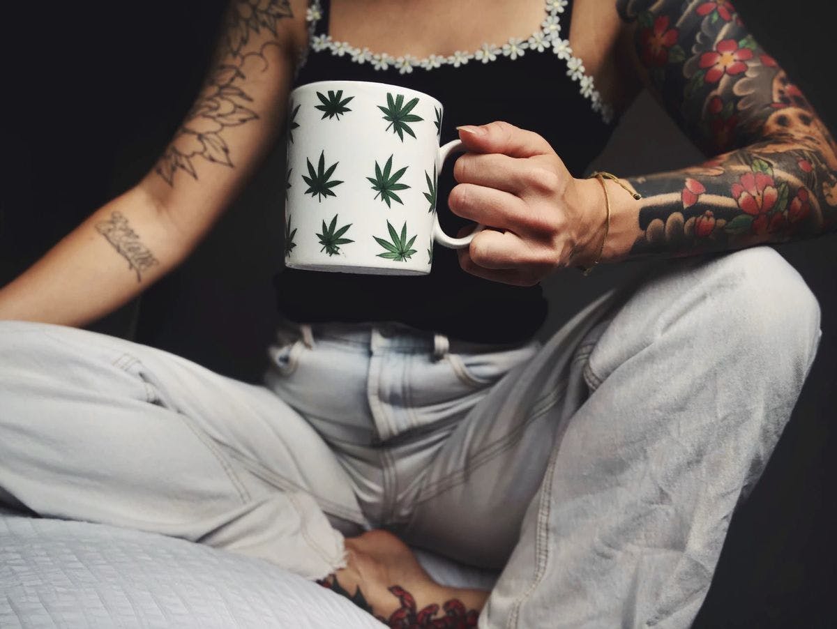 A woman holding a weed-themed mug
