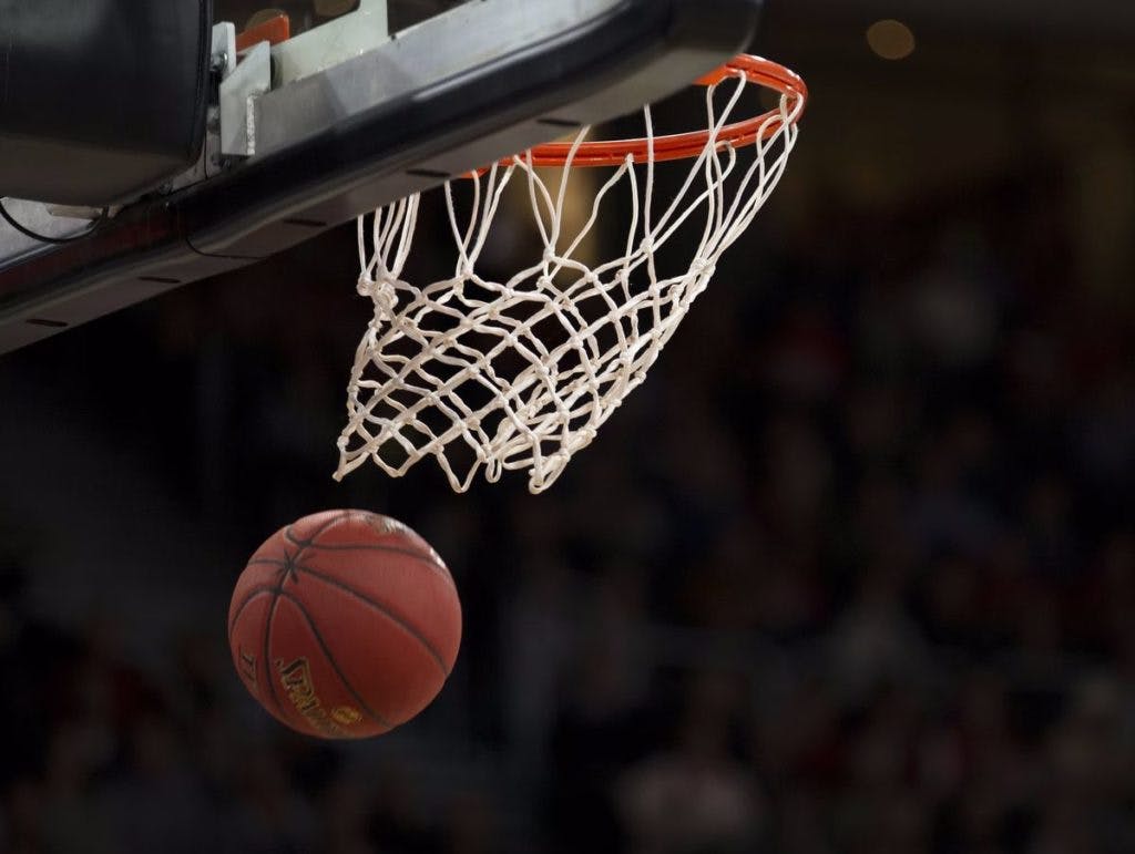 A basketball going through the net, by Marcus Spiske via Unsplash