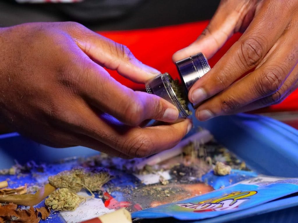 A man closes a weed grinder, filled with cannabis, by Kindel Media via Pexels