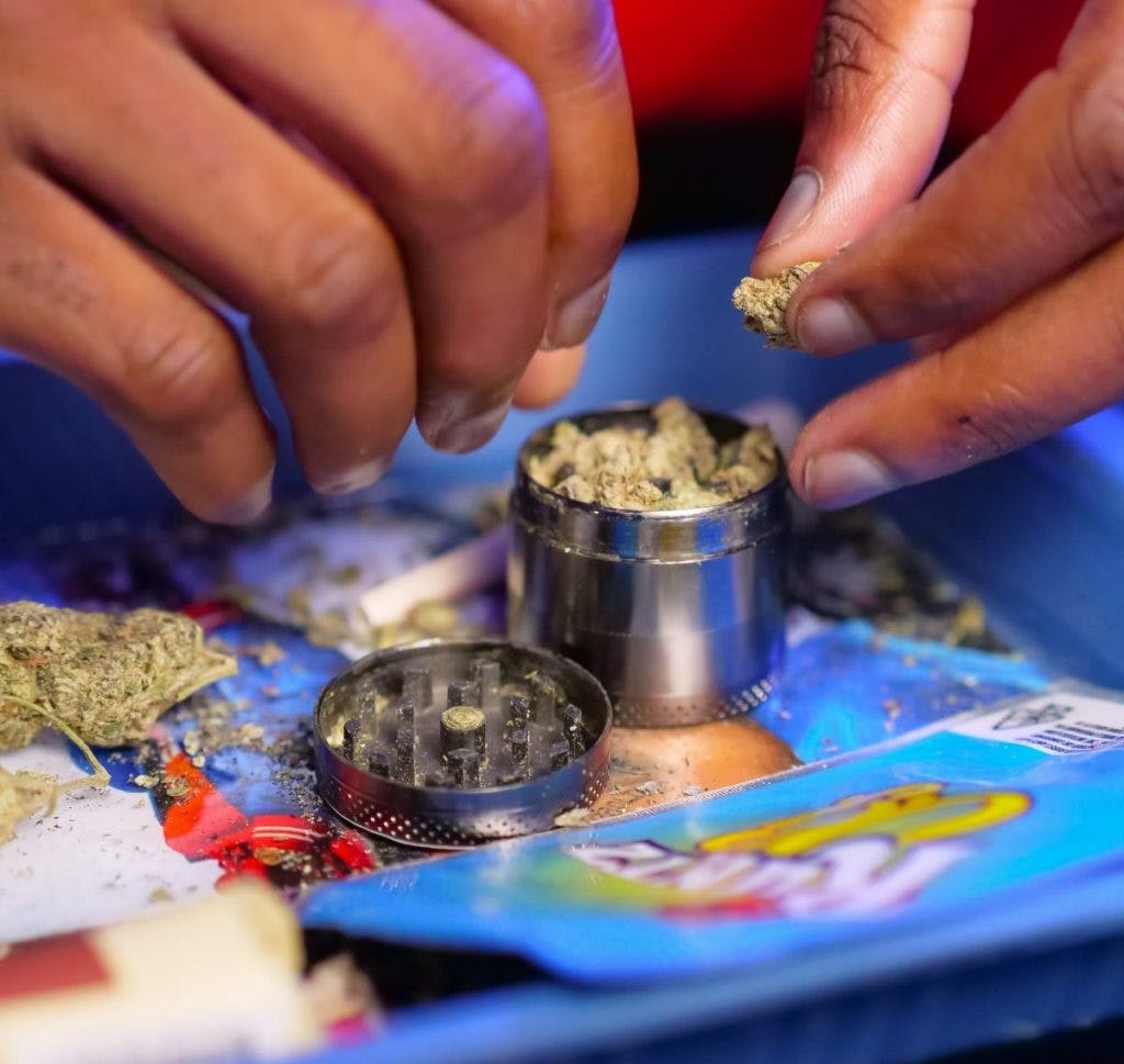 A man putting cannabis into a weed grinder, by Kindel Media via Pexels