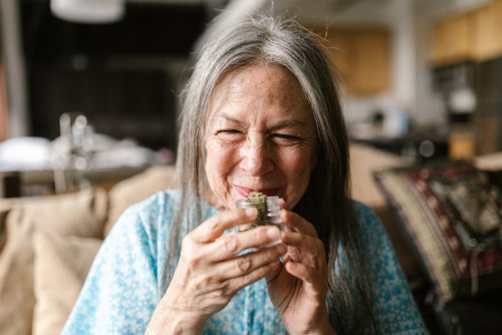 An older woman takes a whiff of some cannabis bud, by RODNAE Productions via Pexels