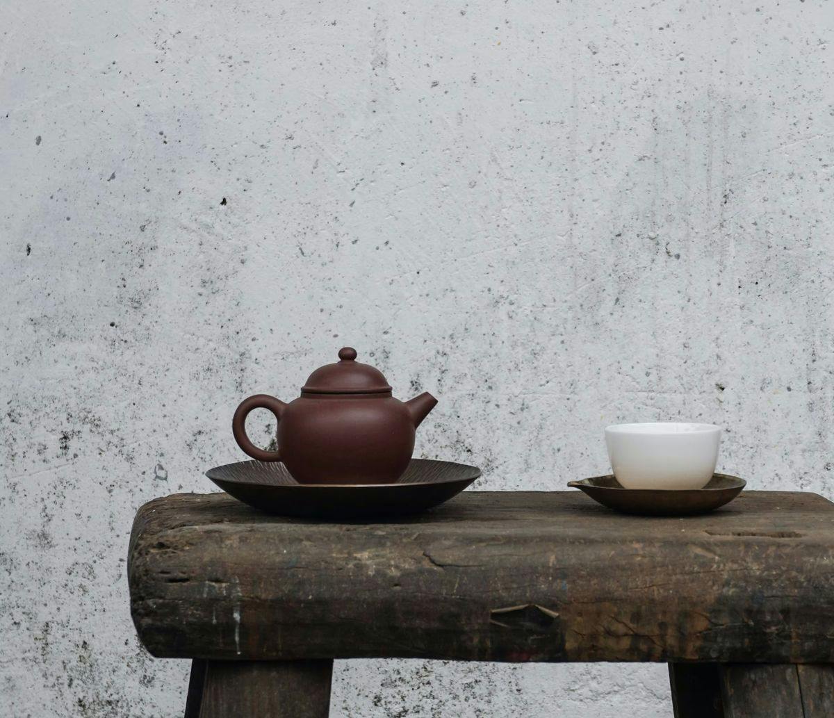 A teapot and tea cup sit atop a wooden table, by Oriento via Unsplash