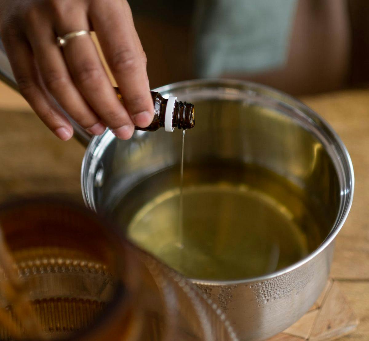 A hand pours a concentrate into a pot of oil for infusing, by Ron Lach via Pexels