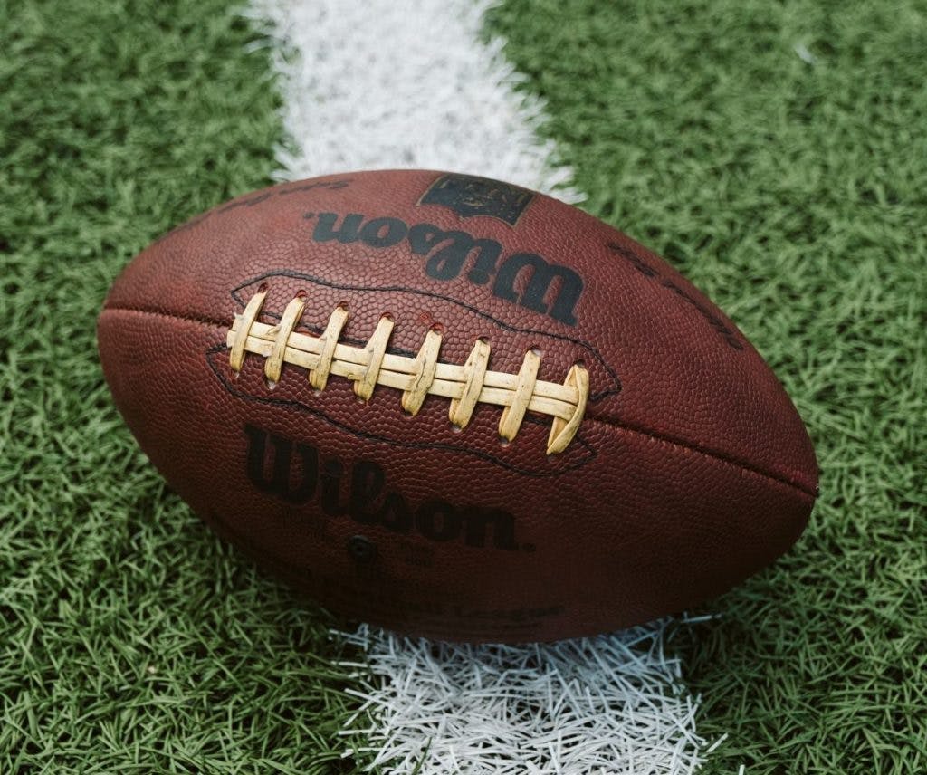 A Wilson football on grass, by Dave Adamson via Unsplash