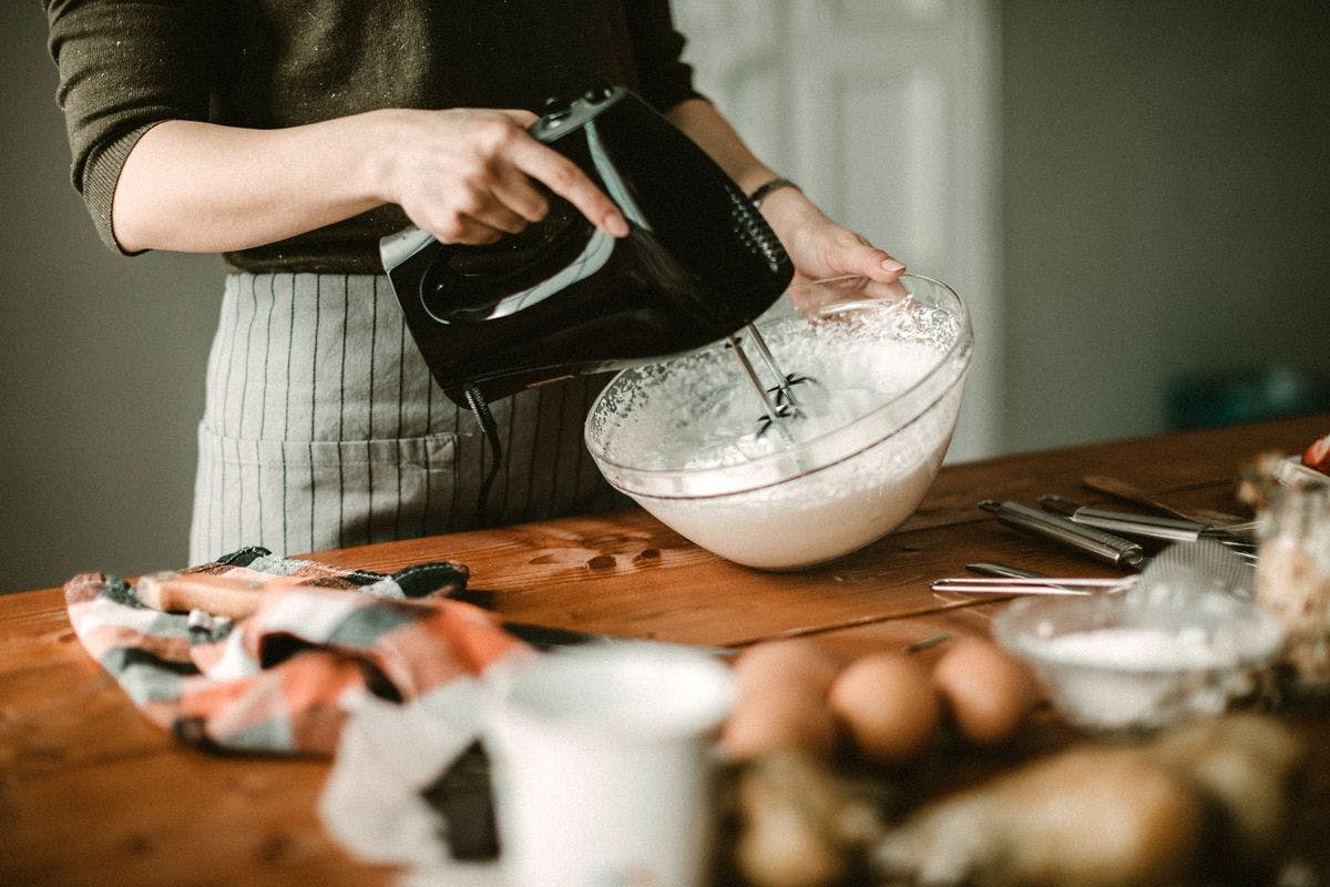 A woman makes whipped cream at home, by eclipse images via iStock