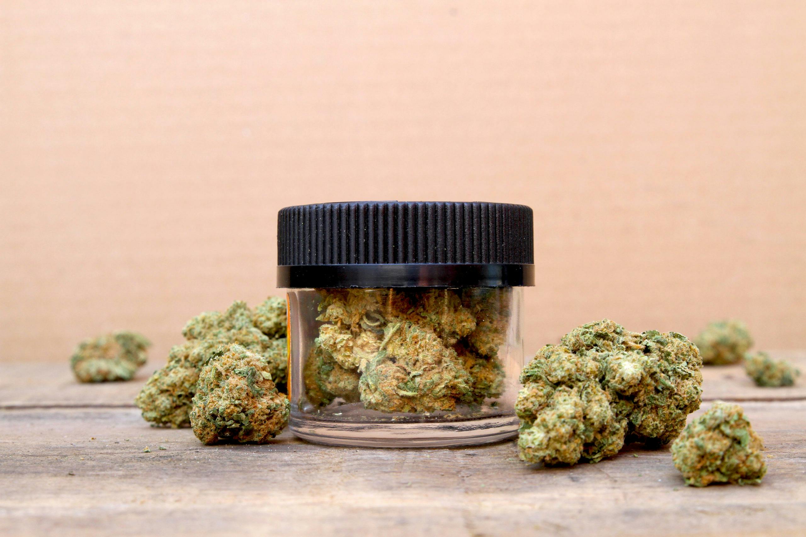 Illicit Cannabis in Jar Surrounded by Buds on Table (Green Crack, Sativ
