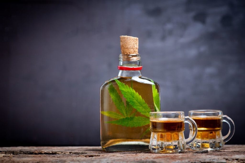 A glass bottle of alcohol, with cannabis leaves inside, by Stefan Tomic via iStock