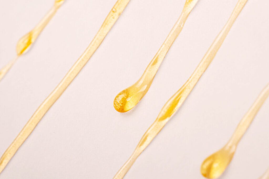 cannabis wax resin dripping down white paper closeup made from DIY rosin press at home
